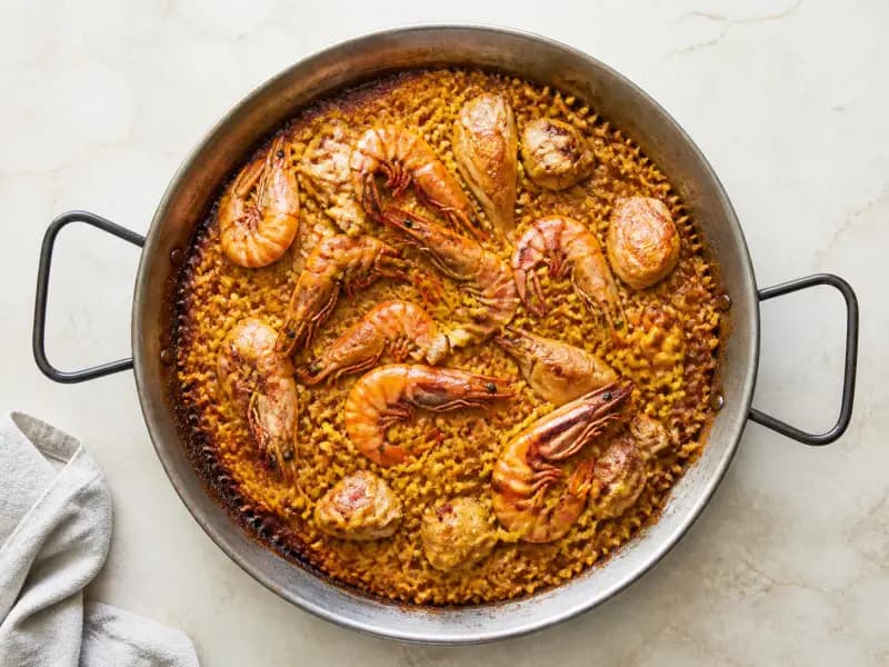 Chicken and Prawn Paella — shot from directly overhead: bomba rice cooked flat and never stirred in a wide pan