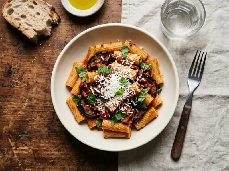 Pasta alla Norma — shot from directly overhead: fried aubergine folded through a simple tomato sauce with torn basil and salted ricotta