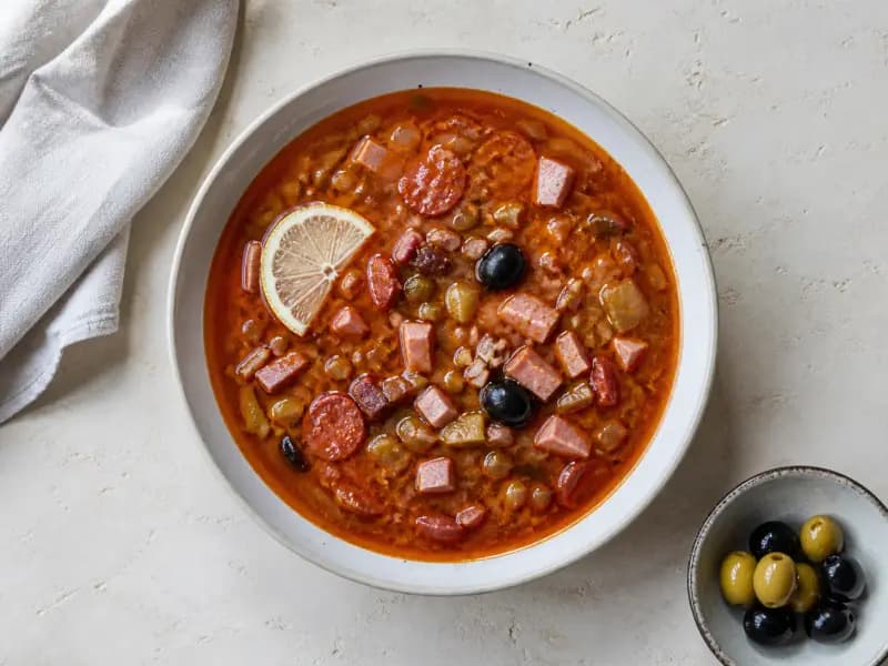Solyanka — shot from directly overhead: a thick sour-salty soup of mixed cured meats